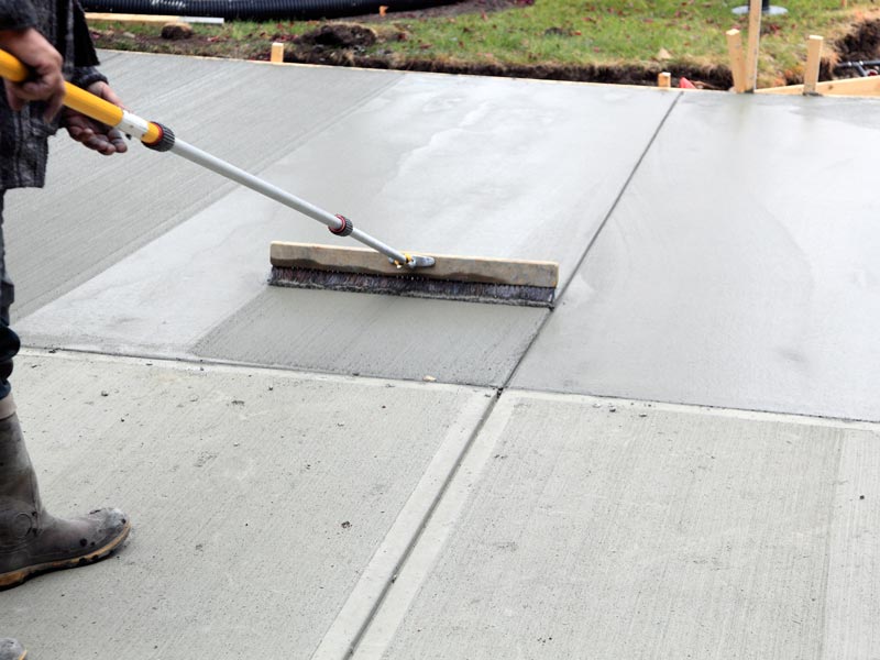Man leveling spreading wet concrete. | concrete repair company in rockwall, tx