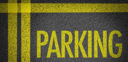 Yellow PARKING stenciling in dark pavement with horizontal and vertical crossing yellow painted lines