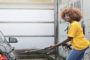 Woman in Yellow Shirt Pressure Washing a Black Vehicle | Soft Washing & High-Pressure Washing